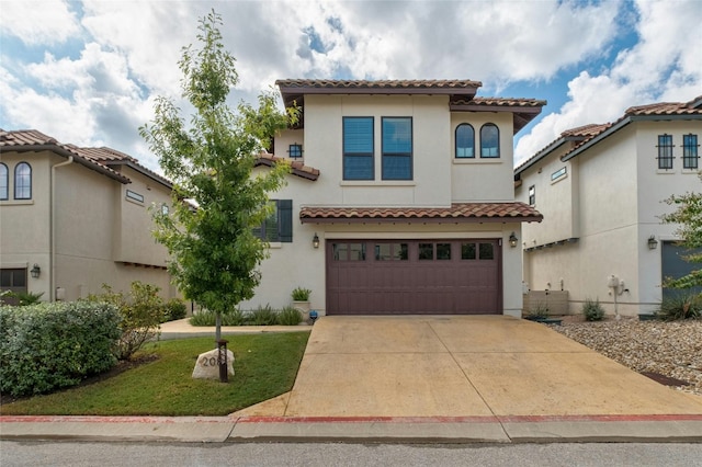 mediterranean / spanish-style house featuring driveway, an attached garage, a tiled roof, and stucco siding