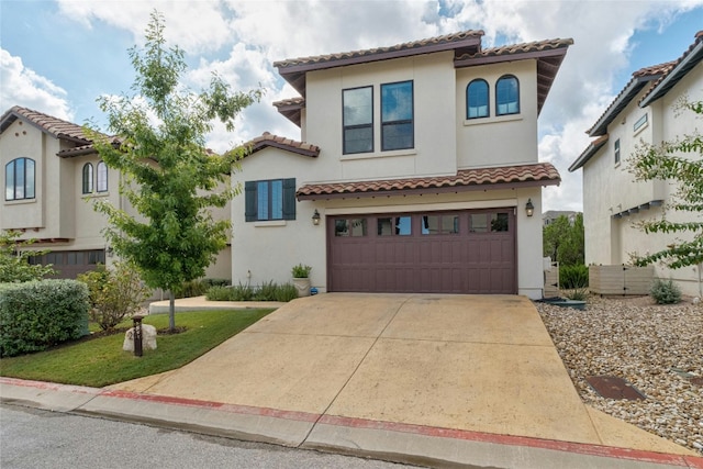 mediterranean / spanish home with a garage, driveway, a tiled roof, and stucco siding