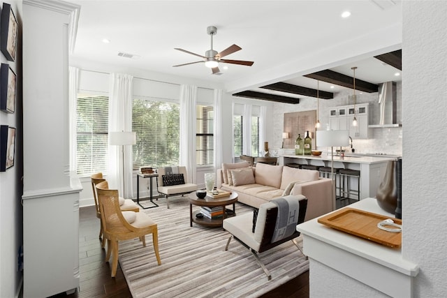 living area featuring a ceiling fan, recessed lighting, beamed ceiling, and wood finished floors