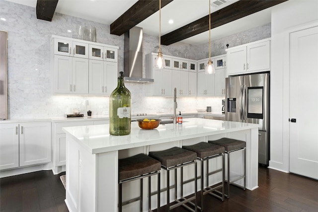 kitchen with decorative backsplash, stainless steel fridge with ice dispenser, light countertops, wall chimney range hood, and white cabinetry