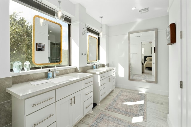 ensuite bathroom featuring two vanities, a sink, a healthy amount of sunlight, visible vents, and a shower stall