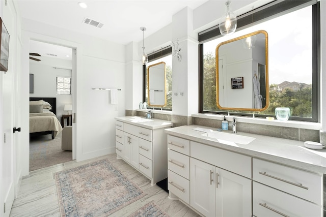 ensuite bathroom with connected bathroom, two vanities, a sink, and visible vents