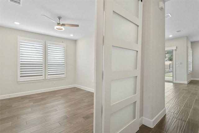 empty room featuring baseboards, a ceiling fan, wood finished floors, and visible vents