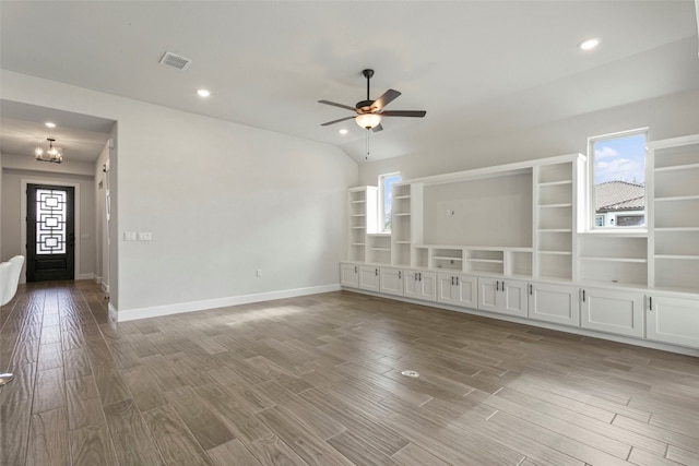 unfurnished living room with baseboards, ceiling fan with notable chandelier, wood finished floors, and visible vents