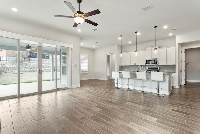 living area with ceiling fan, visible vents, baseboards, and wood finished floors