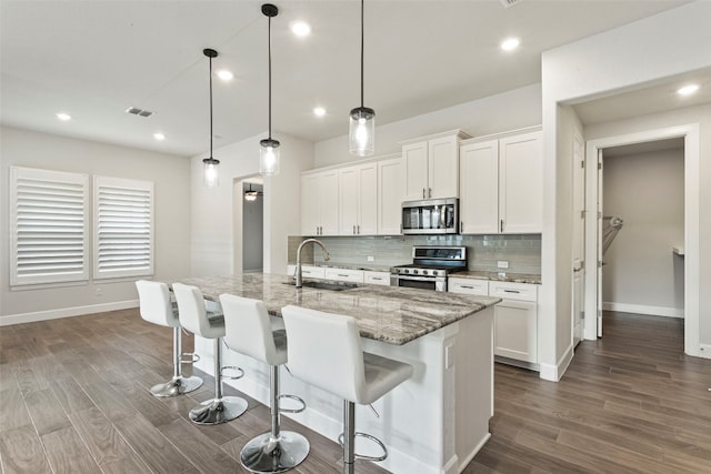kitchen with backsplash, baseboards, appliances with stainless steel finishes, and a sink