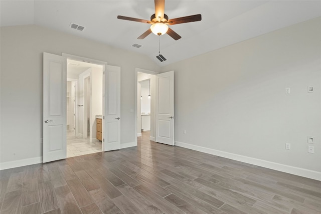 unfurnished bedroom featuring visible vents, wood finished floors, and vaulted ceiling