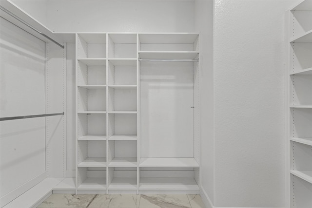 walk in closet featuring marble finish floor