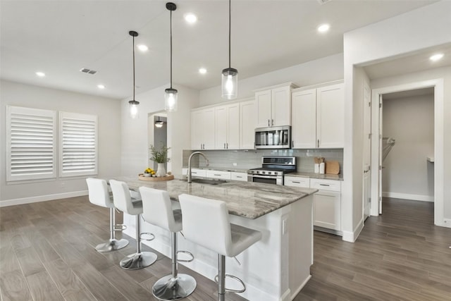 211 Singing Sumac Way, San Marcos, TX 78666 - kitchen featuring appliances with stainless steel finishes, backsplash, dark wood-type flooring, a kitchen breakfast bar, and recessed lighting