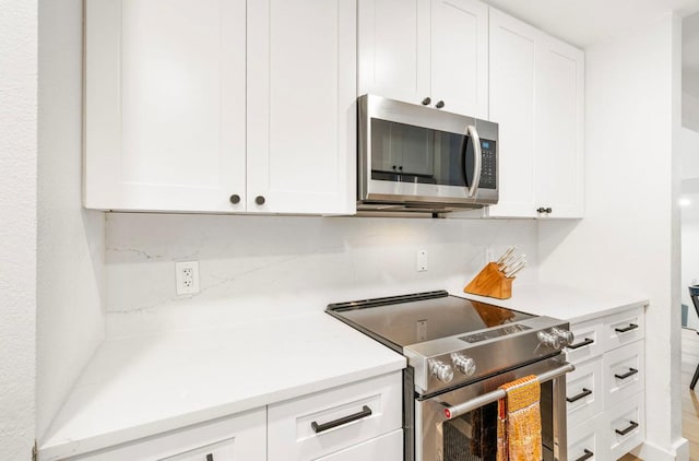 kitchen with stainless steel appliances, light countertops, and white cabinets