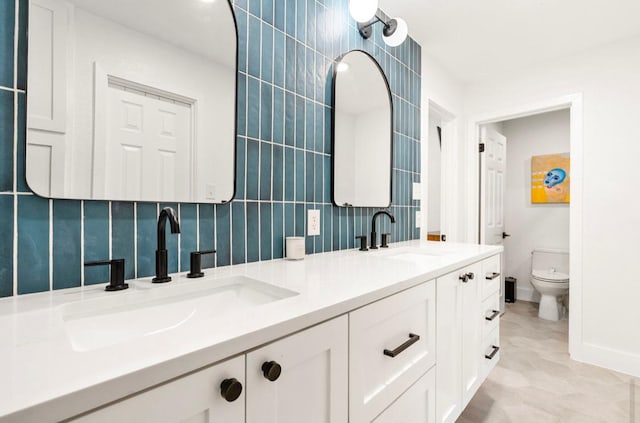 bathroom with double vanity, a sink, toilet, and tile walls