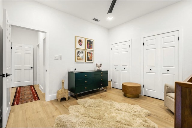 living area featuring ceiling fan, light wood-type flooring, visible vents, and baseboards