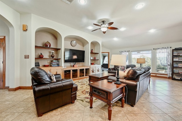 living area with built in shelves, a ceiling fan, arched walkways, and light tile patterned floors