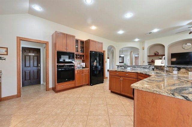 kitchen with built in features, brown cabinets, glass insert cabinets, a sink, and black appliances