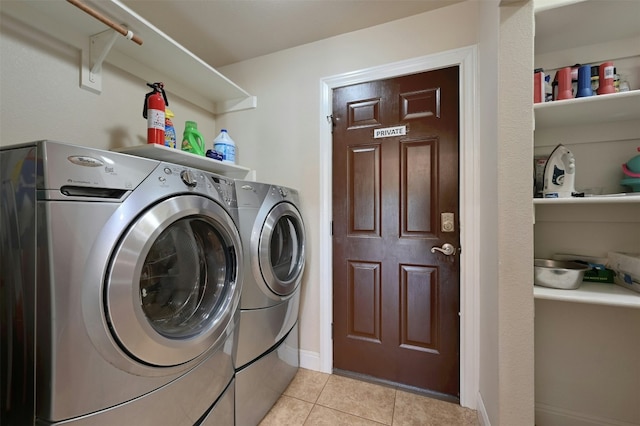 washroom with laundry area, light tile patterned floors, baseboards, and washer and clothes dryer