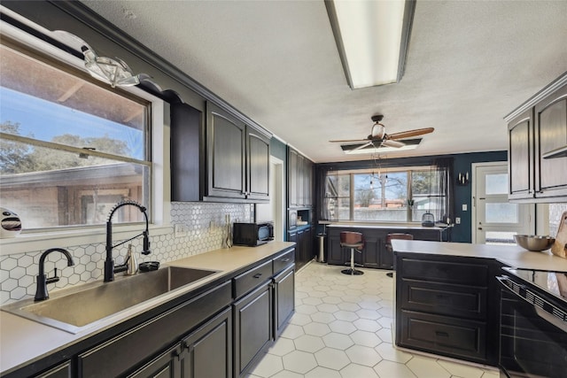 kitchen with tasteful backsplash, a ceiling fan, light countertops, black appliances, and a sink