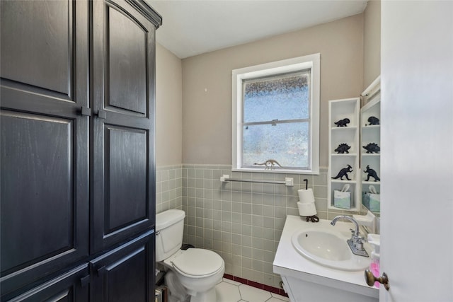 bathroom with tile walls, toilet, wainscoting, vanity, and tile patterned flooring