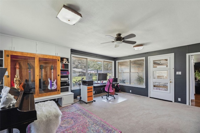 carpeted office space featuring ceiling fan and a textured ceiling