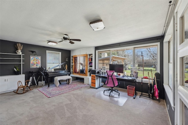 home office featuring carpet floors, ceiling fan, and a textured ceiling