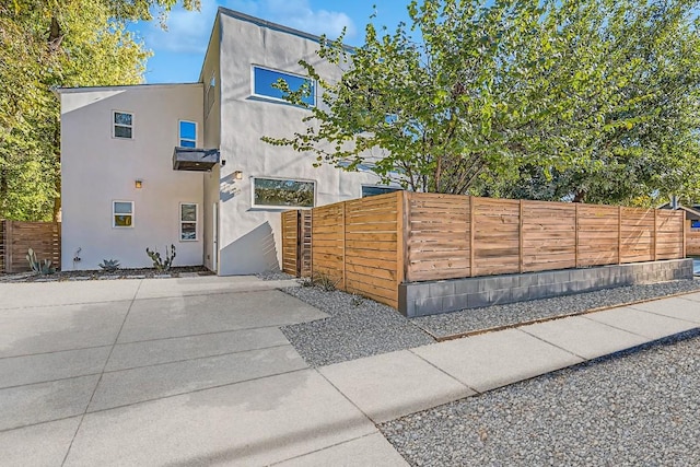 view of front of home with a patio area, fence, and stucco siding