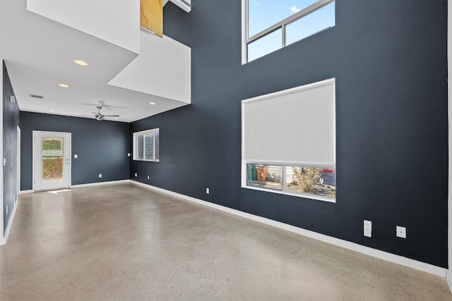 unfurnished room with a high ceiling, recessed lighting, a wealth of natural light, and baseboards