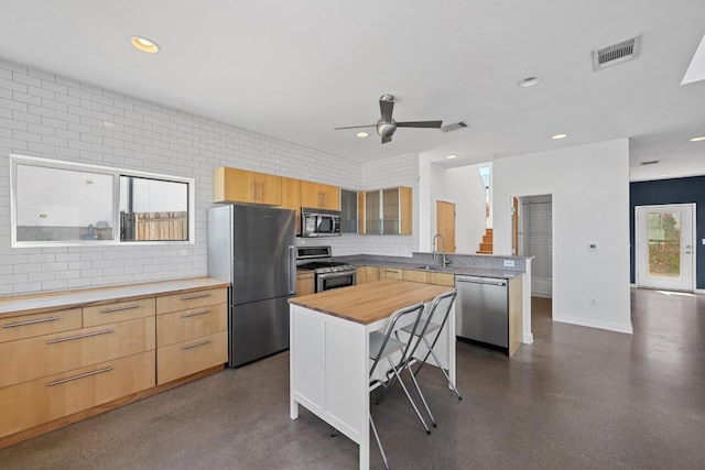 kitchen with visible vents, appliances with stainless steel finishes, a sink, wood counters, and a peninsula