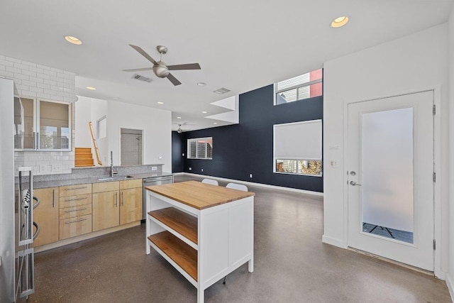 kitchen featuring open shelves, decorative backsplash, stainless steel dishwasher, light brown cabinetry, and a sink