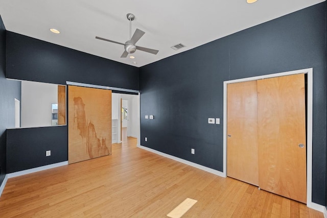 unfurnished bedroom with a ceiling fan, visible vents, baseboards, and wood finished floors