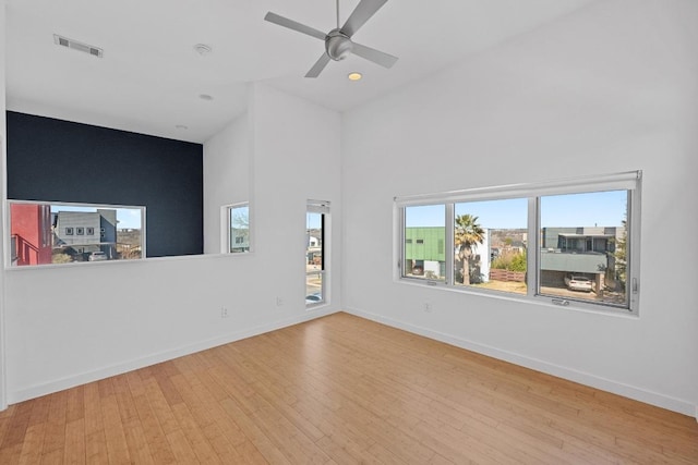 spare room with a towering ceiling, hardwood / wood-style flooring, baseboards, and visible vents