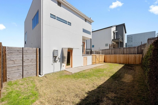 back of property with stucco siding, a fenced backyard, and a yard