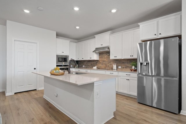 3008 Ottaviano Way, Hutto, TX 78634 - kitchen with appliances with stainless steel finishes, under cabinet range hood, decorative backsplash, light wood-style floors, and white cabinets