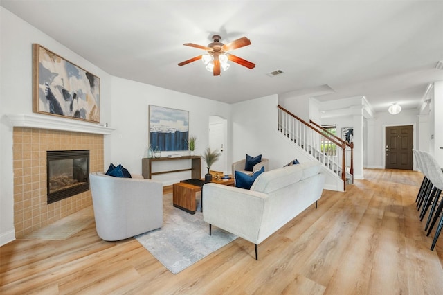 living area with stairs, visible vents, wood finished floors, and a tile fireplace