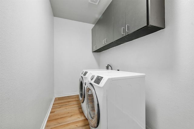 laundry area featuring cabinet space, visible vents, baseboards, light wood-type flooring, and separate washer and dryer