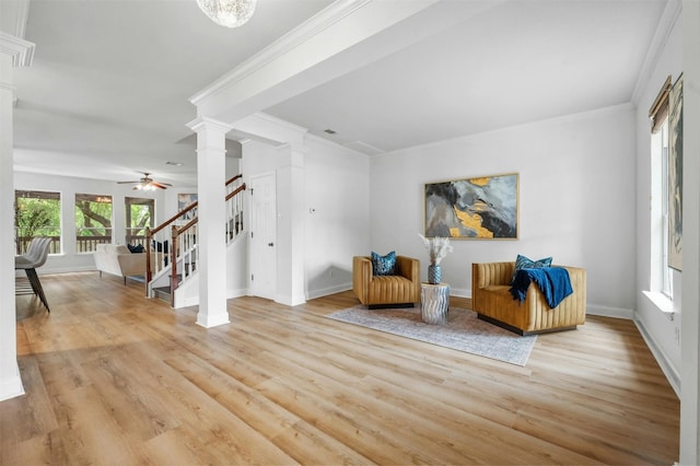 sitting room featuring stairway, light wood-type flooring, decorative columns, and crown molding