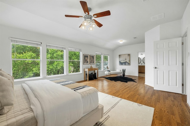 bedroom with vaulted ceiling, wood finished floors, visible vents, and a ceiling fan