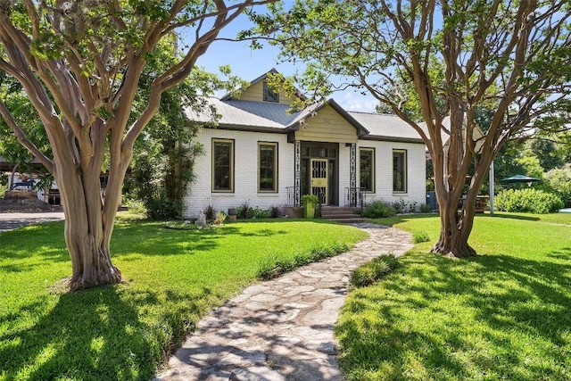 view of front facade featuring metal roof, a front lawn, and brick siding