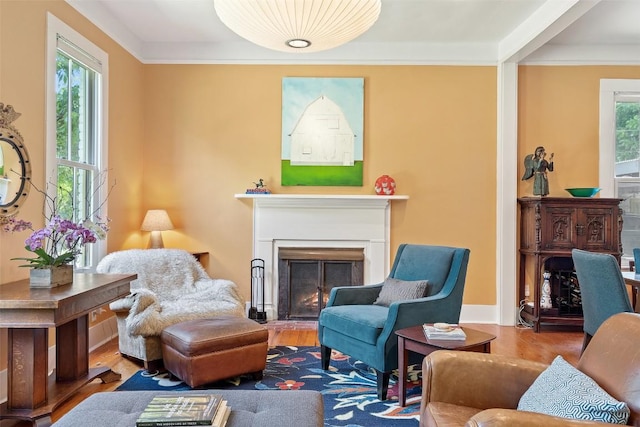 sitting room with a lit fireplace, crown molding, and wood finished floors