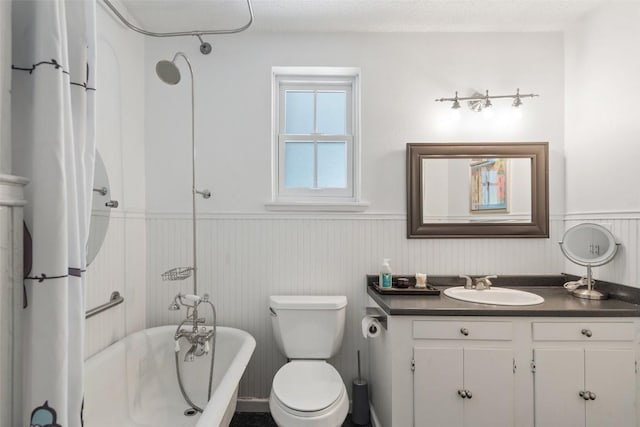 full bath featuring wainscoting, a soaking tub, toilet, and vanity