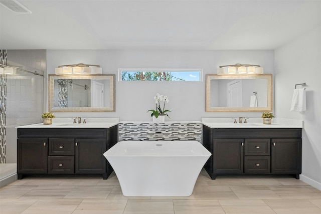 bathroom with a soaking tub, a shower stall, two vanities, and a sink