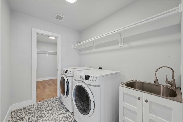 laundry room with washer and clothes dryer, a sink, visible vents, and baseboards