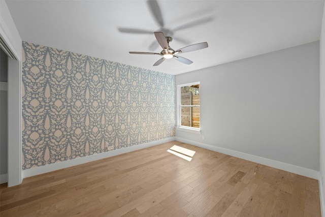 empty room with baseboards, wood finished floors, a ceiling fan, and wallpapered walls