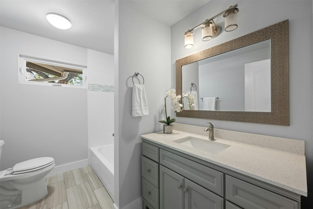 bathroom featuring toilet, baseboards, and vanity