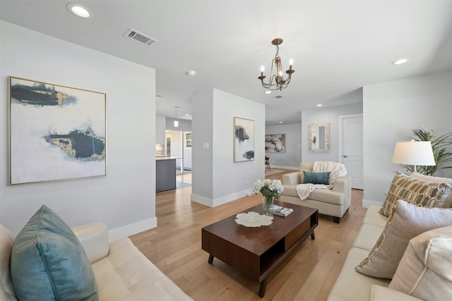 living area featuring baseboards, visible vents, light wood-type flooring, a notable chandelier, and recessed lighting