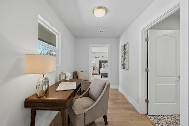 home office featuring baseboards, visible vents, plenty of natural light, and light wood finished floors