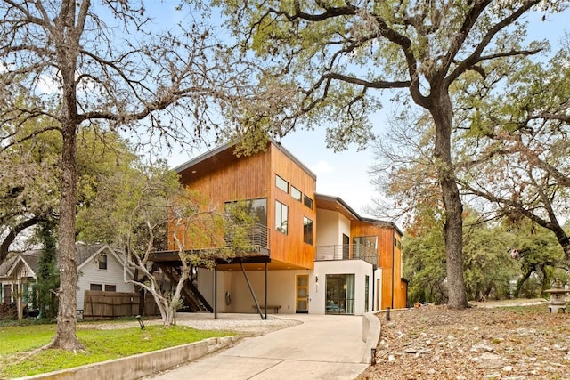 view of front of home featuring fence, stairway, and a balcony