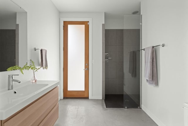 full bathroom with concrete floors, a tile shower, vanity, and baseboards