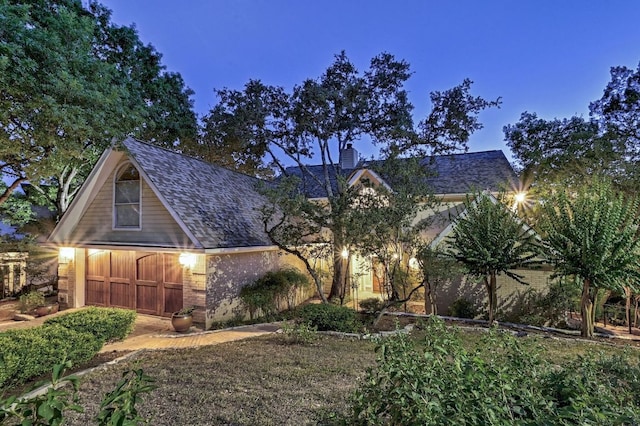 view of front of home featuring brick siding, a chimney, and an outdoor structure