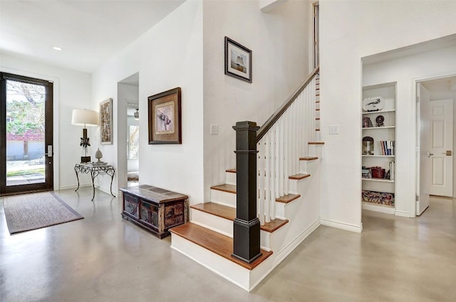 foyer with baseboards, concrete floors, and stairway