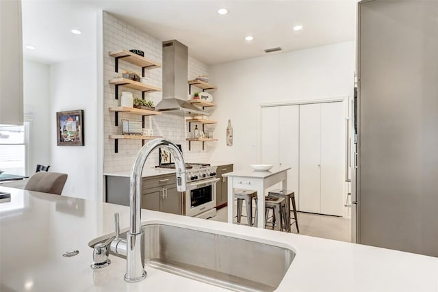 kitchen featuring open shelves, light countertops, visible vents, decorative backsplash, and wall chimney range hood