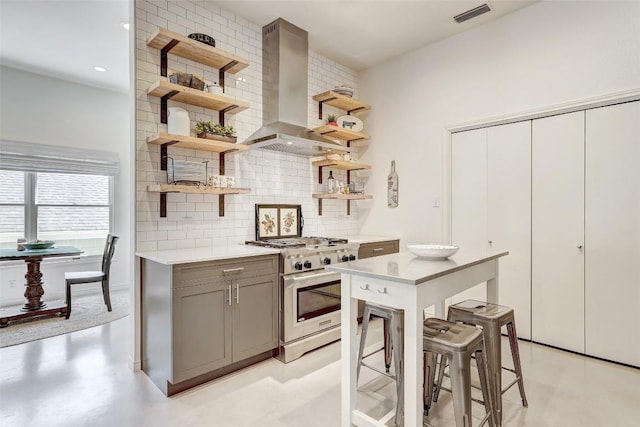 kitchen with visible vents, wall chimney exhaust hood, high end stainless steel range, gray cabinets, and open shelves